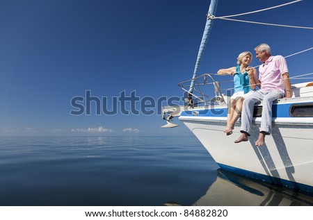 A happy senior couple sitting on the front of a sail boat on a calm blue sea Royalty-Free Stock Photo #84882820
