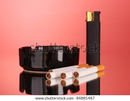 Cigarettes, ashtray and lighter on red background