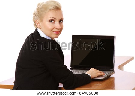 A portrait of a businesswoman sitting at a desk with a laptop, looking back
