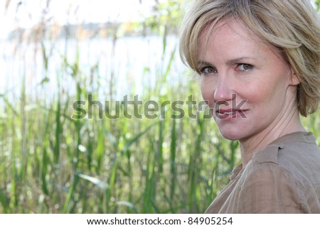 Head shot of woman by reeds on sunny day