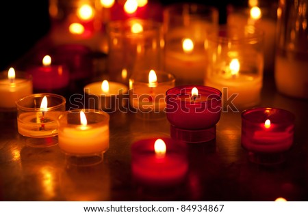 Church candles in red and yellow transparent chandeliers