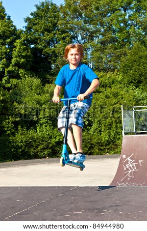 young boy going airborne with his scooter at the skate park