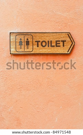 Toilet direction board on the orange wall.