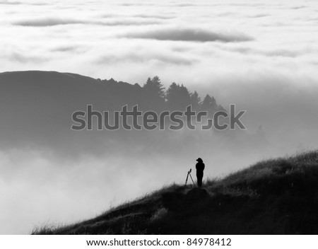 Anonymous silhouette of photographer overlooking a blanket of fog over Pacific Ocean and the Santa Cruz Mountains in California