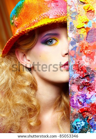 close-up portrait of beautiful woman artist looking from behind of palette