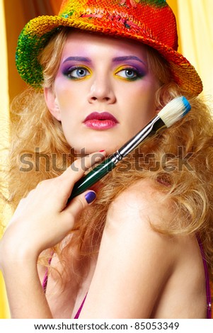 portrait of beautiful blonde woman artist with paintbrush in colorful hat