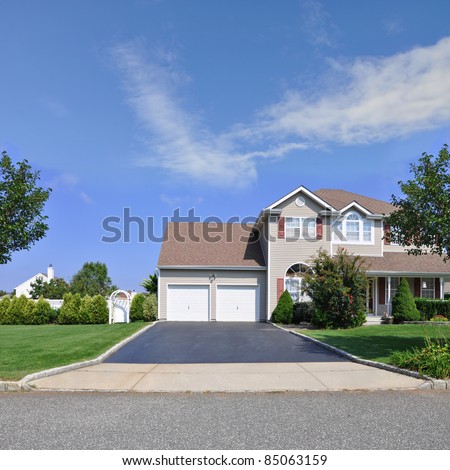 Blacktop Driveway of Split Level Suburban Home with Double Garage Door Two Story Residence in Residential Neighborhood Royalty-Free Stock Photo #85063159