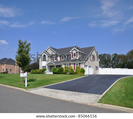 Suburban Two Story Double Garage Home with Fancy Blacktop Cobble Stone Driveway Mailbox on Curb Sunny Blue Sky Day Royalty-Free Stock Photo #85066156