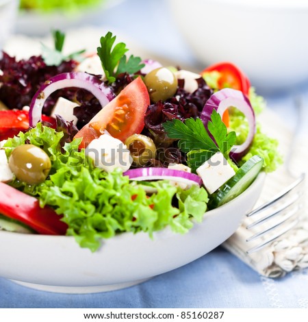 Greek salad with juicy tomatoes, feta cheese,  lettuce, green olives, cucumber, red onion and fresh parsley. Homemade food. Symbolic image. Concept for a tasty and healthy vegetarian meal. Close up.  Royalty-Free Stock Photo #85160287