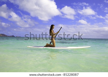 beautiful brunette in bikini on paddle board in hawaii