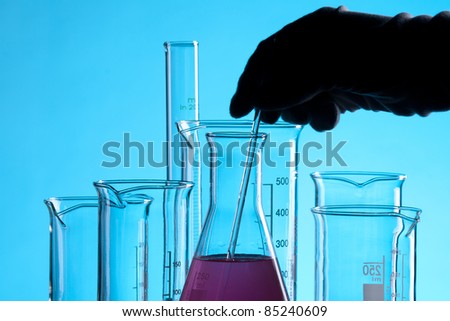 Laboratory technician working with laboratory glassware - chemical flasks with one colored solution.