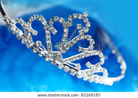 Close-up photo of the silver diadem with diamonds on a blue background with bokeh
