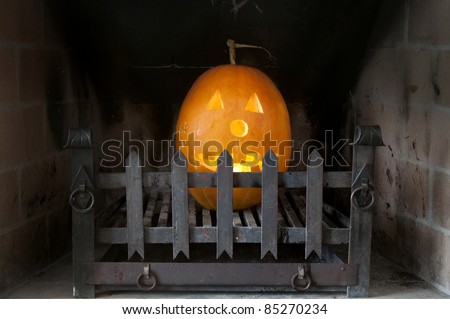 Halloween pumpkin with light in a dark fire place