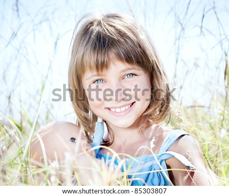 Portrait of attractive beautiful young girl with children's doll in his hand, among the tall grass