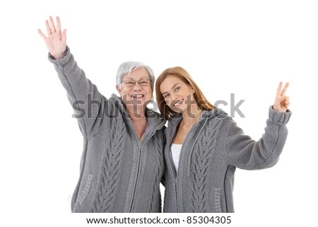 Senior mother and young daughter wearing the same cardigan, embracing each other, smiling happily.?