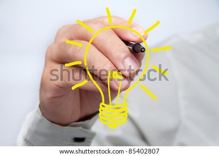 Hand with a pen drawing light bulb.