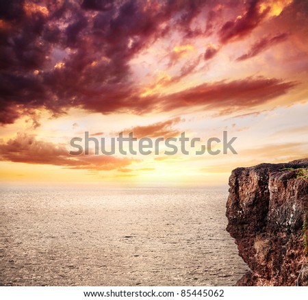 Beautiful background of ocean, cliff and sunset orange sky with clouds. Free space for text or man
