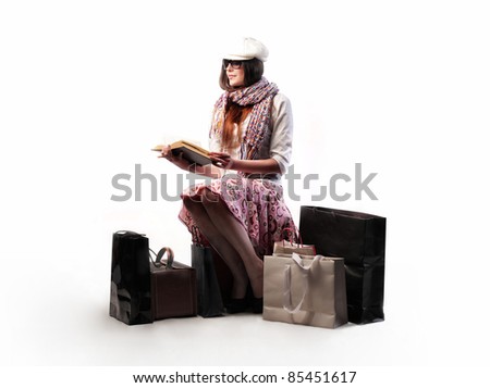 Beautiful woman sitting on a suitcase and reading a book