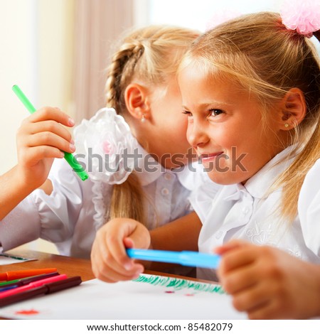 Two little girls gossip in classroom