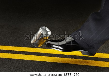 close up of politician's shoe kicking a dented shiny can down the road Royalty-Free Stock Photo #85554970
