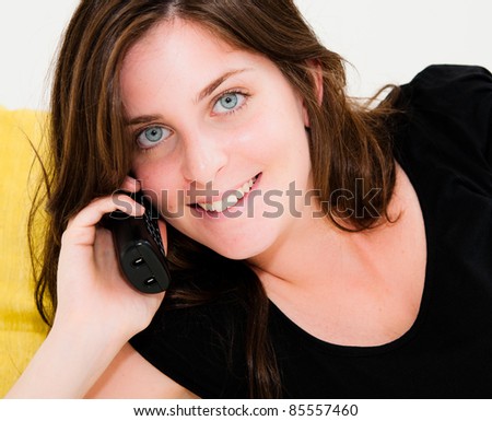 Beautiful happy woman on a white sofa making a phone call