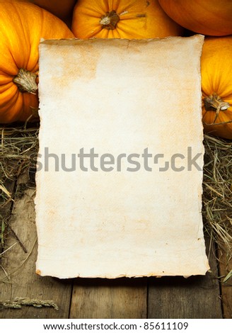 orange pumpkins and  sheet of paper on wooden background