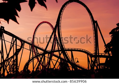silhouette of a roller coaster at a purple sunset during a fun fair, after a sunny day