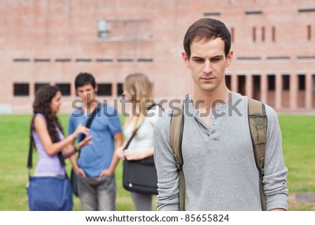 Lonely student posing while his classmates are talking outside a building Royalty-Free Stock Photo #85655824