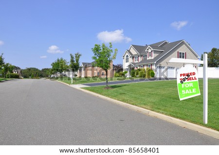 Real Estate For Sale Sign on Front Yard Lawn of Large Luxury Two Car Garage Suburban Home in Residential Neighborhood Sunny Blue Sky Day