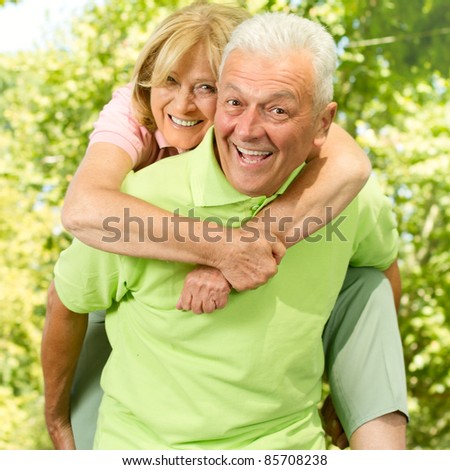 Portrait of happy senior man giving piggyback ride outdoors.