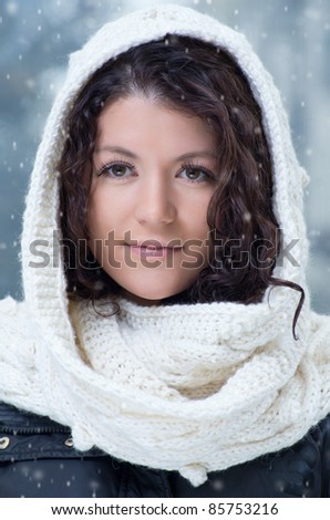 Pretty young caucasian brunette woman wearing white scarf with hood in a outdoor winter portrait