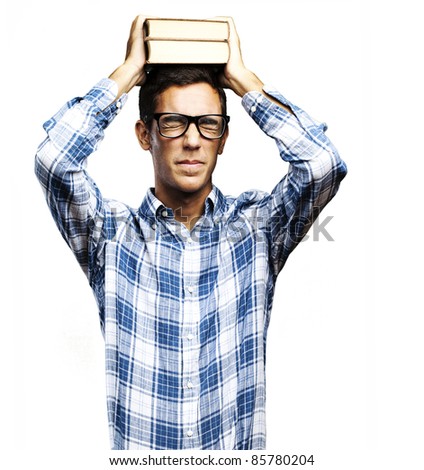 portrait of young man with glasses holding books on his head over white background