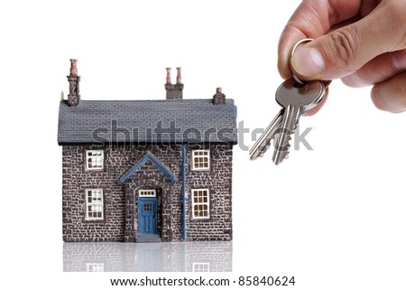 Holding house keys in front of a model of a house concept for real estate sale or rental