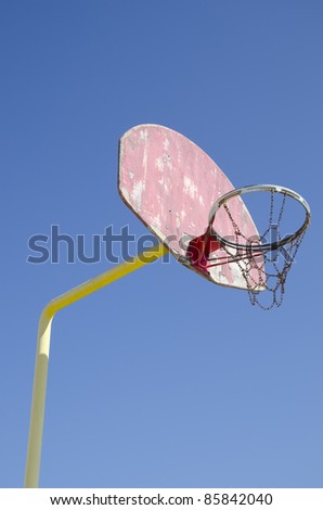 A battered basketball hoop and backboard on an urban playground