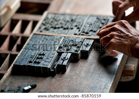 The old man arrange letterpress for press on paper. This is a art of typography of ancient printing industry. Typeset design is relate craft. The vintage type is still open nowadays.