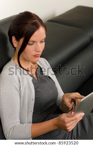 Elegant businesswoman on stylish leather sofa working touch tablet computer