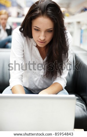 Portrait of a beautiful young woman working on laptop while sitting at cafe or shopping mall