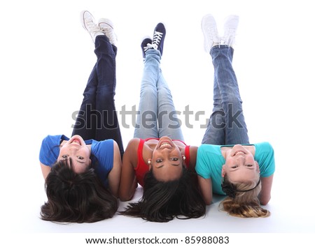 Teenage school student best friends lying on the floor looking backwards together made up of mixed race african american, oriental Japanese and caucasian all with happy smiles having a laugh.