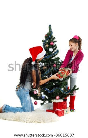 Mother and daughter near a christmas tree with gifts, isolated on a white background
