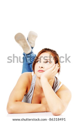 Front view of thoughtful teen girl lying on her tummy and looking on upper left corner, on white background