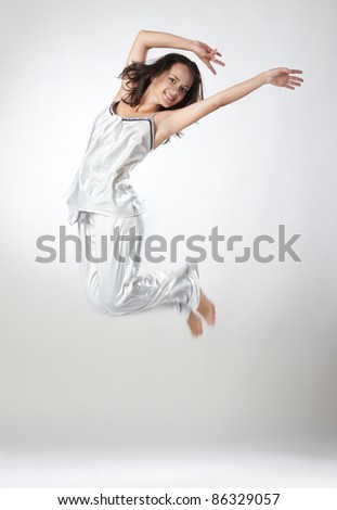 Young cute girl gracefully dances in a studio, isolated over white background