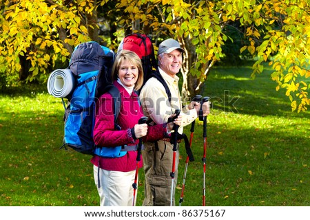 Happy senior couple with backpacks and trekking poles.