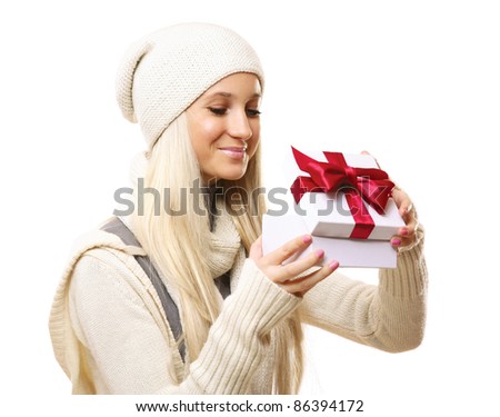 Pretty blonde in winter clothing opening xmas gift isolated on white background