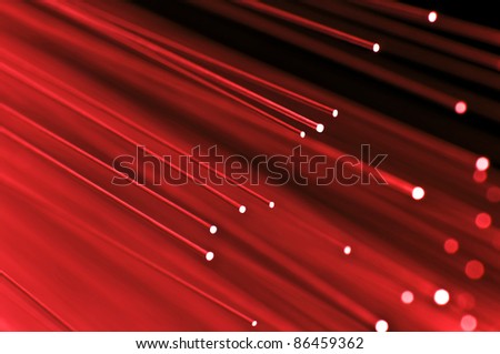 Close up on the ends of a selection of illuminated red fiber optic light strands with black background.