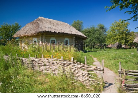 beautiful countryside with old fence and house, blue cloudy sky in background