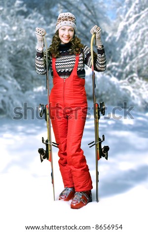 Happy skier. Girl in ski suit holding pair of mountain ski