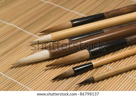 studio photography of various chinese brushes on wooden mat