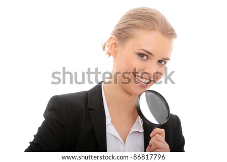 Young attractive smiling business woman looking into a magnifying glass, isolated on white background