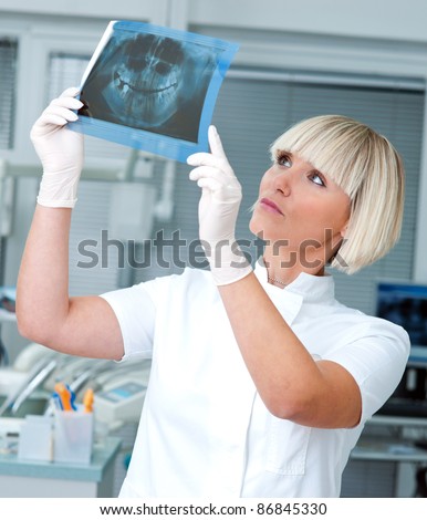 woman dentist looking at x-ray image and thinking