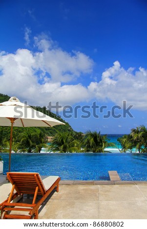 Sunbathing Beds along the swimming pool by the sea, relaxing beach holiday scene with blue sky